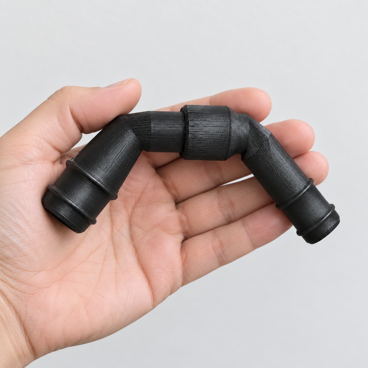 Eheim 12/16mm to 3/4 Inch Vinyl Barb Elbow Adapter, 90 Degree, Black, held in a hand to show its size