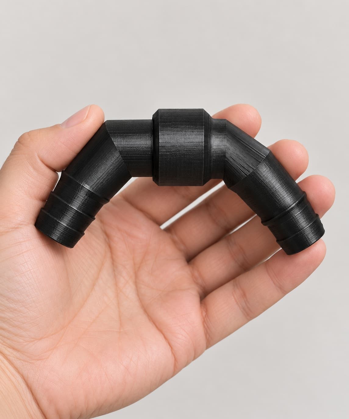 Eheim 16/22mm to 5/8 Inch Vinyl Barb Elbow Adapter, 90 Degree, Black, held in a hand to show its size