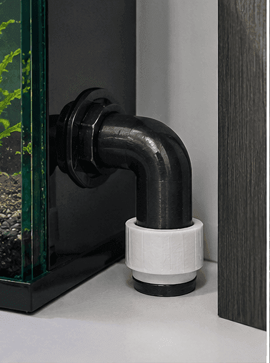 A black printed elbow return plumbed into an aquarium inside its cabinet